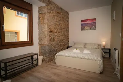 a bedroom with a bed and a stone wall at A Torna in Palas de Rei