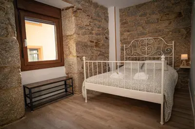 a bedroom with a white bed in a brick wall at A Torna in Palas de Rei