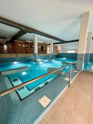 a large swimming pool with blue water in a building at Costa Reinante Spa in San Miguel de Reinante