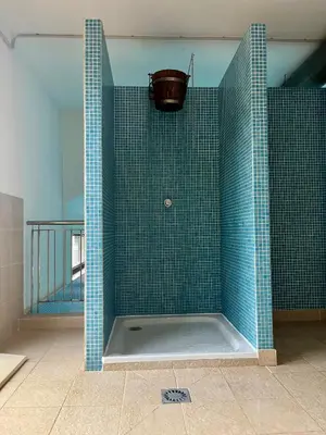 a blue tiled shower with a bucket on the wall at Costa Reinante Spa in San Miguel de Reinante