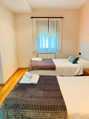 two beds in a room with a window at Hostal Restaurante MarRojo Sanabria in Requejo