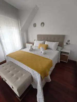 a bedroom with a large white bed with a yellow blanket at Ático las Palmeras in Caldas de Reis