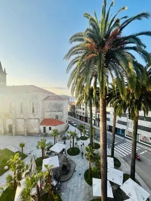 a view of a courtyard with palm trees and a building at Ático las Palmeras in Caldas de Reis