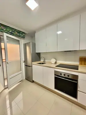 a kitchen with white cabinets and a stainless steel refrigerator at Ático las Palmeras in Caldas de Reis