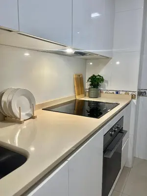 a white kitchen with a sink and a stove at Ático las Palmeras in Caldas de Reis