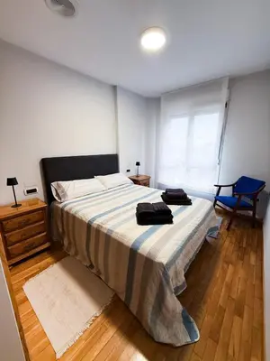 a bedroom with a large bed and a blue chair at San Marcos in Ribadeo