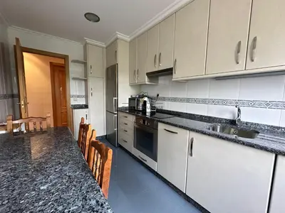 a kitchen with white cabinets and a counter top at Parque Ávila in Ourense