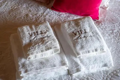 two white towels on a bed with a pink pillow at Villa Limia