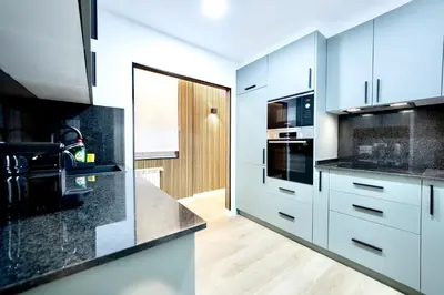 a kitchen with white cabinets and black counter tops at Urban Essences by Lugo Collection in Lugo