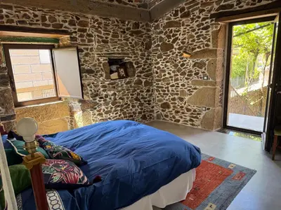 a bedroom with a bed in a stone wall at Casa Vella do Nanín in Faramontaos