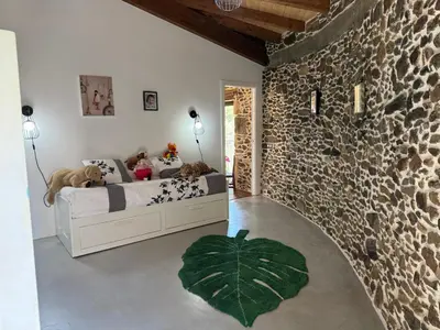 a bedroom with a bed and a stone wall at Casa Vella do Nanín in Faramontaos