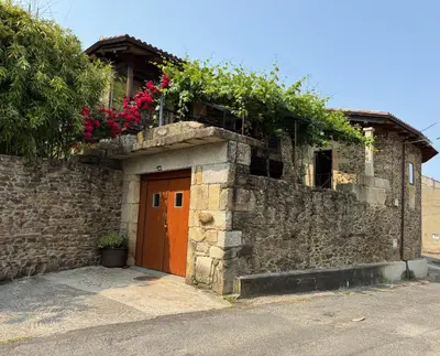 a stone building with flowers on top of it at Casa Vella do Nanín in Faramontaos