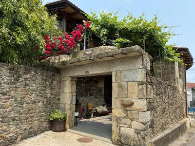 a stone building with flowers on top of it at Casa Vella do Nanín in Faramontaos