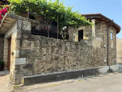 a stone wall with a balcony on top of it at Casa Vella do Nanín in Faramontaos