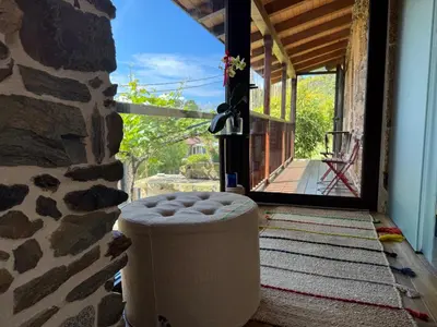 a stool sitting on a porch next to a stone wall at Casa Vella do Nanín in Faramontaos