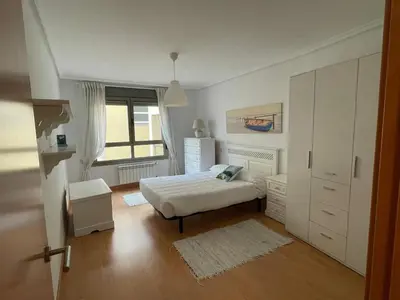 a white bedroom with a bed and a window at EnBURELA Playa in Burela de Cabo