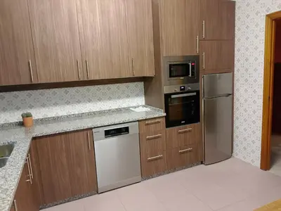 a kitchen with wooden cabinets and stainless steel appliances at Casa Las Catedrales Rochela in Devesa