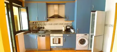 a kitchen with blue cabinets and a washing machine at EnFOZ Duplex En La Playa in Foz