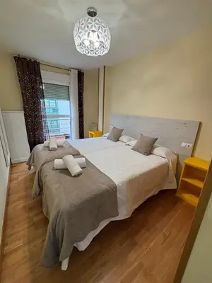 a bedroom with two beds and a chandelier at Alojamiento Morriña in O Pedrouzo