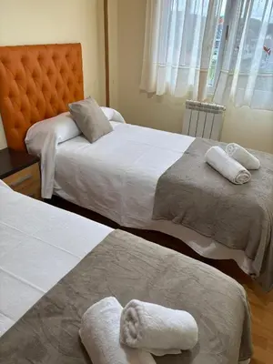 two beds in a bedroom with towels on them at Alojamiento Morriña in O Pedrouzo