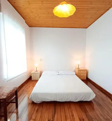 a bedroom with a white bed and a wooden ceiling at Casa das Mariñas in Viveiro