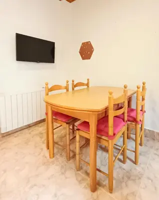 a wooden table with chairs and a tv on a wall at Casa das Mariñas in Viveiro