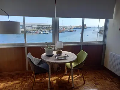 a table and chairs in a room with a view of a harbor at Puerto de Burela in Burela de Cabo