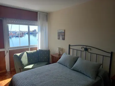 a bedroom with a bed and a chair and a window at Puerto de Burela in Burela de Cabo