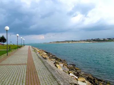 a brick walkway next to the water with a rock wall at EnFOZ Playa A Rapadoira in Foz