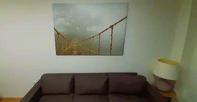 a couch in a living room with a picture of a suspension bridge at EnFOZ Playa A Rapadoira in Foz