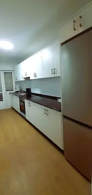 a kitchen with white cabinets and a large refrigerator at EnFOZ Playa A Rapadoira in Foz