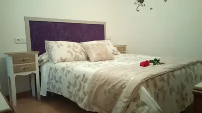 a bed with a white comforter and two roses on it at Apartamento Rio Sar garaje incluido in Santiago de Compostela