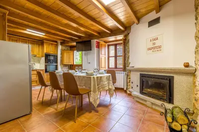 a kitchen and dining room with a table and a fireplace at A Casa do Carpinteiro