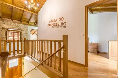 a wooden staircase in a room with a stone wall at A Casa do Carpinteiro