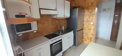 a kitchen with white cabinets and a microwave and a refrigerator at EnSAN CIPRIAN Atico en Urb Río Cobo in San Ciprián