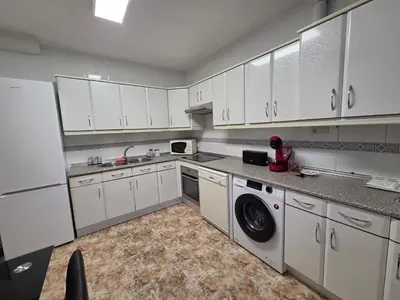 a kitchen with white cabinets and a washer and dryer at Casa Alba in Puebla de Sanabria