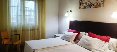 a hotel room with a bed with red and white pillows at Hostal Martin - Sanabria in Ribadelago