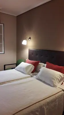 a bedroom with two beds with white and red pillows at Hostal Martin - Sanabria in Ribadelago