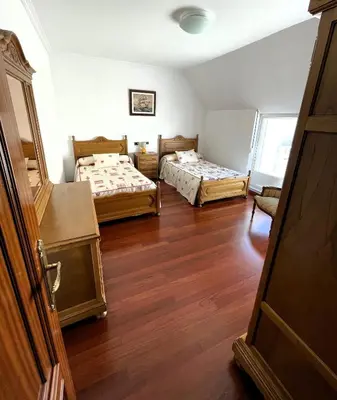 two beds in a room with wooden floors at EnVIVEIRO Villa Bonita in Viveiro