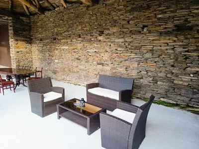 a patio with chairs and a table and a stone wall at Casa Do Castelo in Lugo
