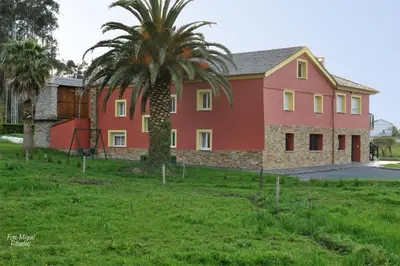 a large red house with a palm tree in front of it at Apartamentos Bouso in Villaframil