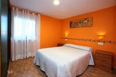 a bedroom with orange walls and a bed and a window at Apartamentos Bouso in Villaframil
