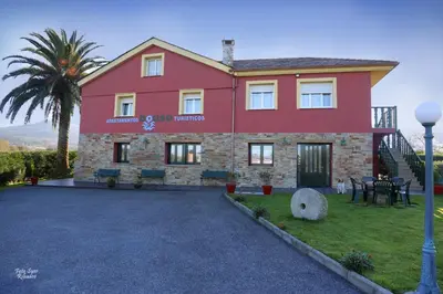 a red house with a palm tree in front of it at Apartamentos Bouso in Villaframil