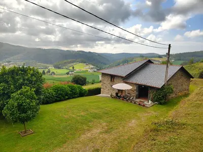 a small stone house on a hill with mountains in the background at La casa de atrás in Arancedo