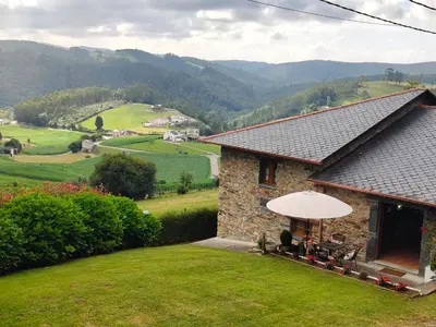a house with a table and chairs and an umbrella at La casa de atrás in Arancedo