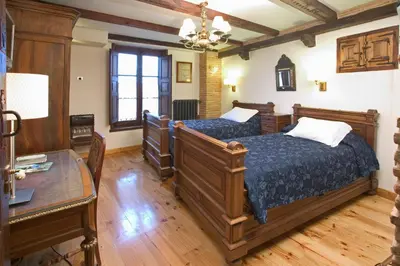 a bedroom with two beds and a table in it at Hostería Camino in Luyego de Somoza