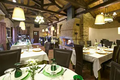 a restaurant with white tables and chairs and a fireplace at Hostería Camino in Luyego de Somoza