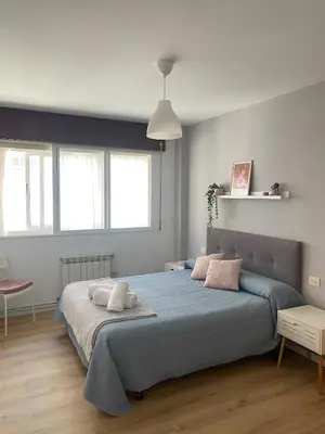 a bedroom with a large bed with blue sheets and pink pillows at Apartmento O Río in Burela de Cabo
