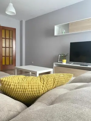 a living room with a couch with a yellow throw pillow at Apartmento O Río in Burela de Cabo