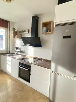 a kitchen with white cabinets and a stainless steel refrigerator at Apartmento O Río in Burela de Cabo